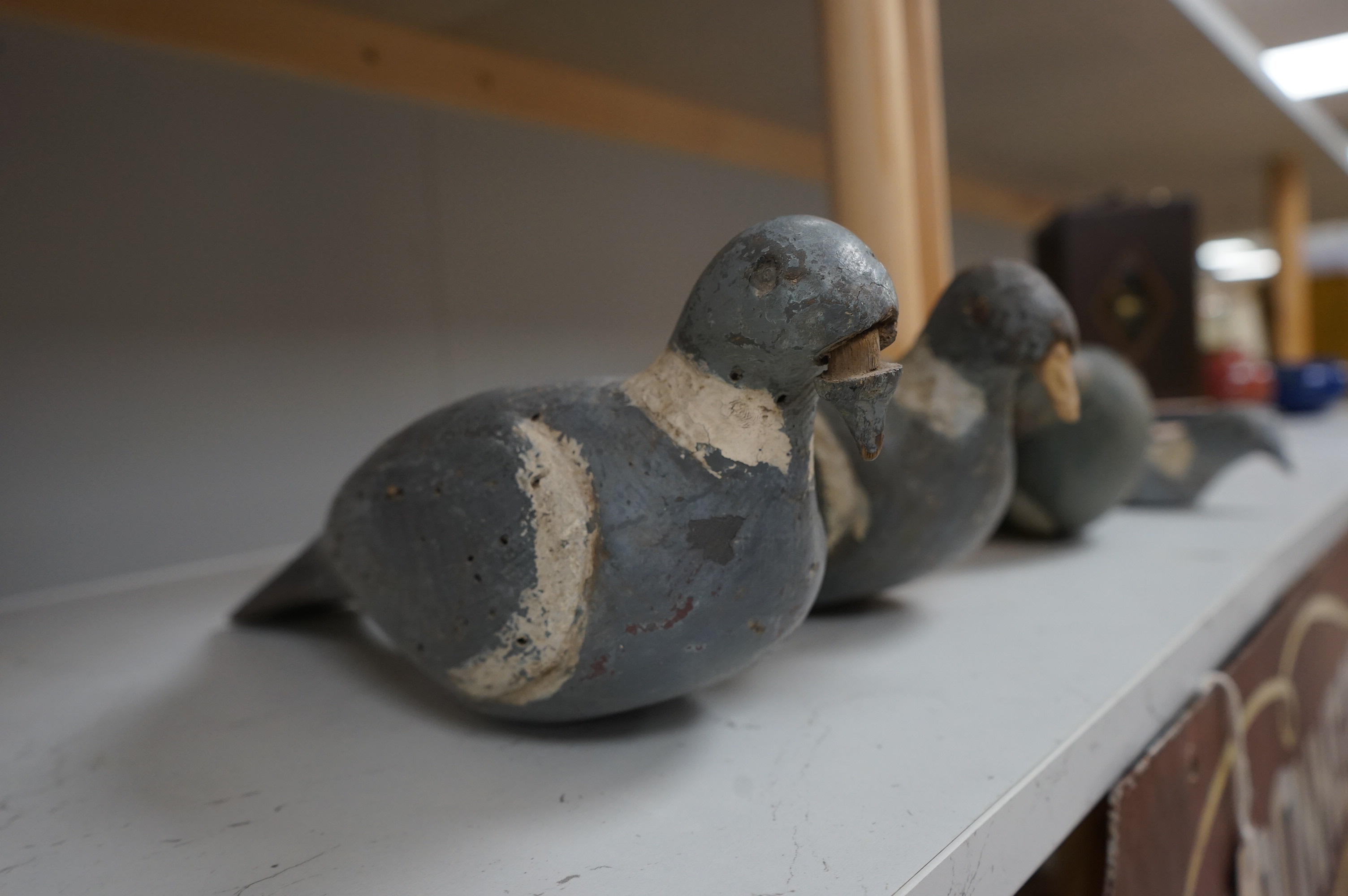 Three early 20th century carved wood decoy pigeons and a later cast metal decoy. Largest 35cm long. Condition - variable